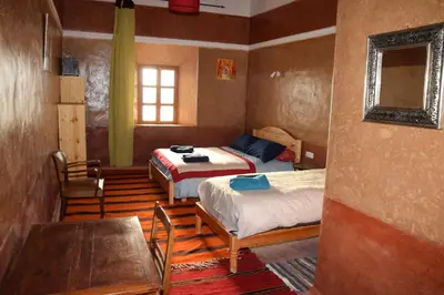 a bedroom with two beds and a table and chairs at KASBAH ALTAÏR in Kalaat MGouna