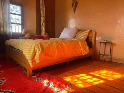a bedroom with a bed with an orange comforter at KASBAH ALTAÏR in Kalaat MGouna