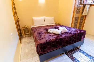 a bedroom with a purple bed with two towels on it at Riad Batha in Fès
