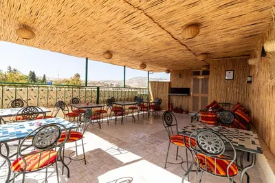an outdoor patio with tables and chairs and windows at Riad Batha in Fès