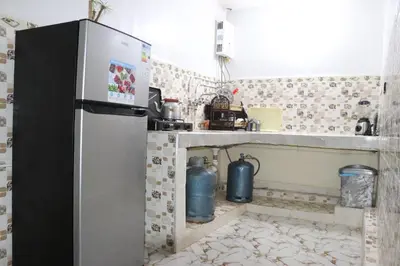 a kitchen with a refrigerator and a tiled floor at Résidence SEHRAWILOCATION in Er Rachidia