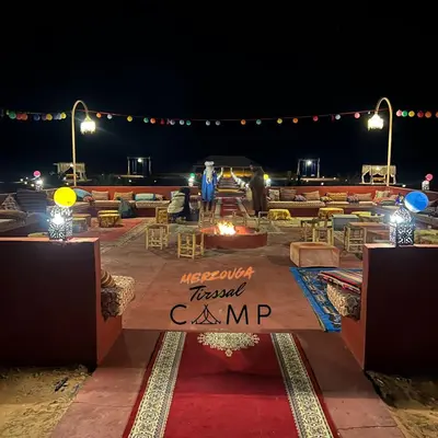 a large amphitheater with tables and chairs at night at Merzouga Tirssal Camp in Merzouga