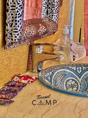 a table with a plate and a bottle of water at Merzouga Tirssal Camp in Merzouga