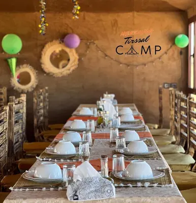 a long table with plates and napkins on it at Merzouga Tirssal Camp in Merzouga