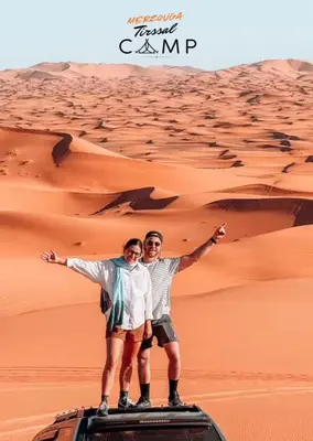 two men standing on top of a vehicle in the desert at Merzouga Tirssal Camp in Merzouga