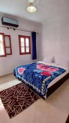 a bedroom with a bed with a blue blanket on it at Warzazat Apartments in Ouarzazate