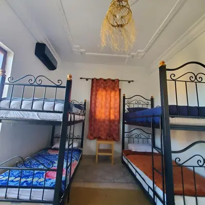 a room with three bunk beds and a chandelier at WARZAZAT Hostel in Ouarzazate