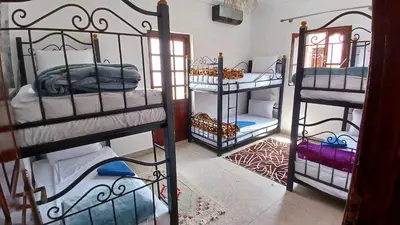 a room with three bunk beds in a room at WARZAZAT Hostel in Ouarzazate
