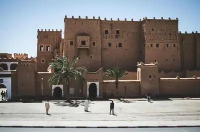 people standing in front of a large building at WARZAZAT Hostel in Ouarzazate