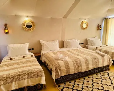 a bedroom with two beds and a mirror on the wall at Sahara Berber Luxury Camp in Merzouga