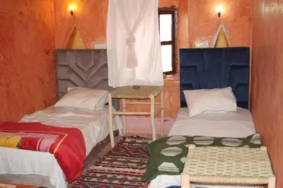 a room with two beds and a chair in it at Dar adiafa dar asalam in Aït Ben Haddou