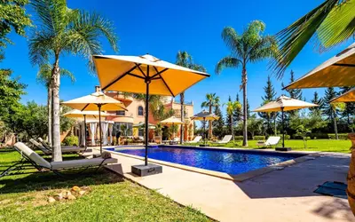 a swimming pool with umbrellas and palm trees at Dar Biona in Marrakech