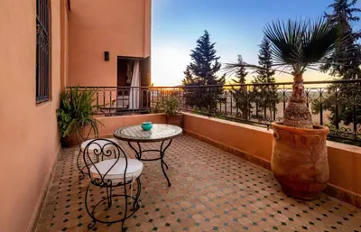 a balcony with a table and chairs and a palm tree at Dar Biona in Marrakech