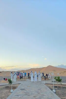 a group of people in white robes standing in the desert at Merzouga Night Camp in Merzouga