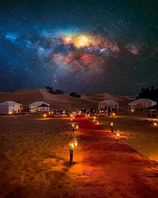 a starry night with a group of lights in the desert at Merzouga Night Camp in Merzouga