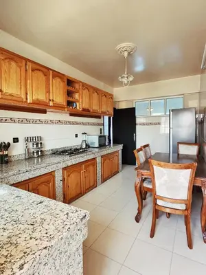 a kitchen with wooden cabinets and a table and chairs at logement exceptionnel réservé aux familles in Meknès