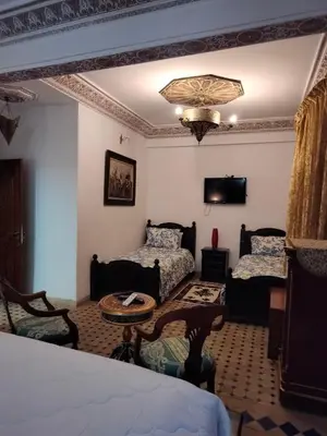 a bedroom with a bed and a couch and a table at Riad Laraichi Palace Suites in Fès
