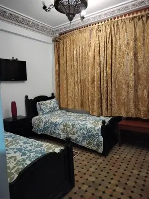 a bedroom with two beds and a window with curtains at Riad Laraichi Palace Suites in Fès