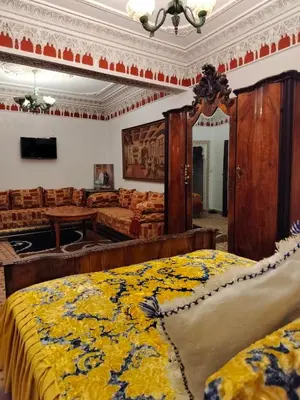 a bedroom with two beds and a yellow and blue blanket at Riad Laraichi Palace Suites in Fès