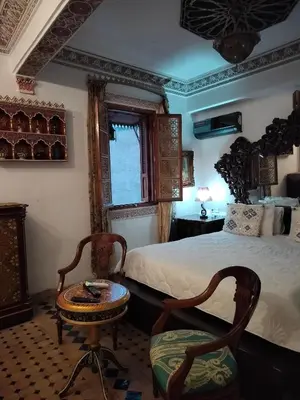 a bedroom with a bed and a table and a chair at Riad Laraichi Palace Suites in Fès