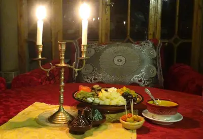 a table with a plate of food and two candles at Kasbah Itrane in Tamnougalt
