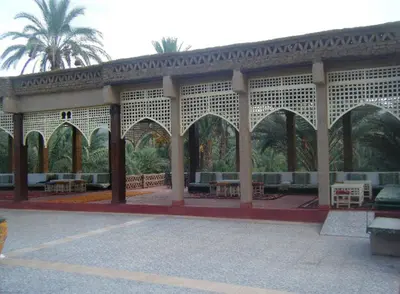 a pavilion with tables and palm trees in a park at Kasbah Itrane in Tamnougalt