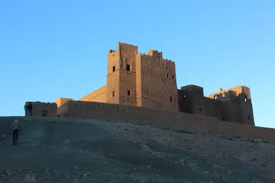 a man walking up a hill in front of a castle at Kasbah Itrane in Tamnougalt