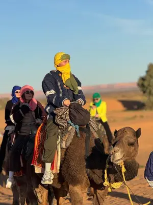 a group of people riding on the back of a camel at Camp Sakura Desert Dream in Merzouga