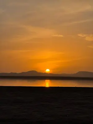 a sunset over the water with the sun in the sky at Camp Sakura Desert Dream in Merzouga