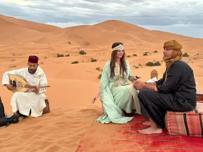 a group of three people sitting in the desert at Camp Sakura Desert Dream in Merzouga