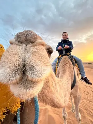 a man riding on the back of a camel in the desert at Camp Sakura Desert Dream in Merzouga