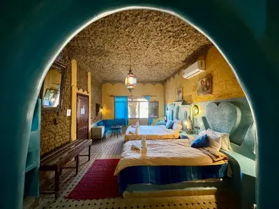 two beds in a room with an archway at Riad Ksar Merzouga in Merzouga