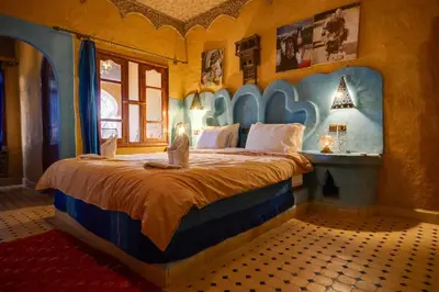 a bedroom with a large bed with a blue headboard at Riad Ksar Merzouga in Merzouga