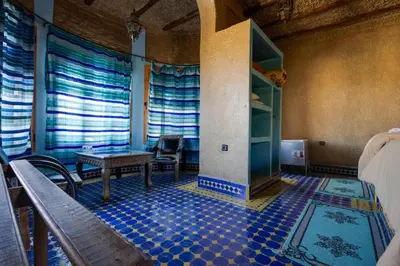 a room with a fireplace and a table and chairs at Riad Ksar Merzouga in Merzouga