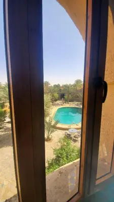 an open door with a view of a swimming pool at Riad Ksar Merzouga in Merzouga