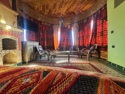 a room with a stage with chairs and a fireplace at Riad Ksar Merzouga in Merzouga