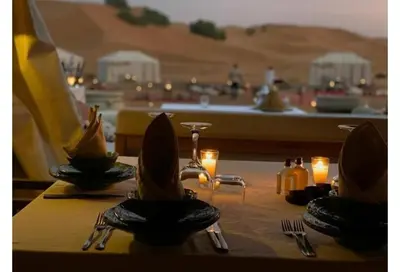 a table with a view of a desert with candles at Merzouga Alicante Luxury Camp in Merzouga
