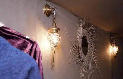 a lamp hanging on a wall next to a mirror at Merzouga Alicante Luxury Camp in Merzouga
