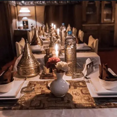 a long table with white plates and vases on it at Merzouga Alicante Luxury Camp in Merzouga