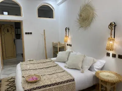 a white bedroom with a bed and a table at Dar Mgouna Roses in Kalaat MGouna