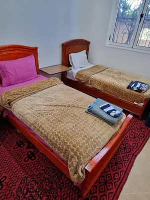 two twin beds in a room with a red carpet at Dar Latifa in Tinerhir