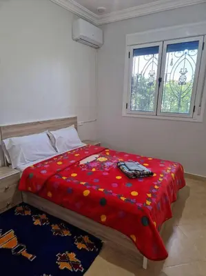 a bedroom with a red comforter on a bed at Dar Latifa in Tinerhir