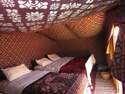 two beds in a room with a wall at Chegaga Berber Camps in Mhamid