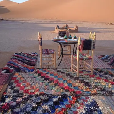 a table and two chairs on a beach with a table and a table at Chegaga Berber Camps in Mhamid
