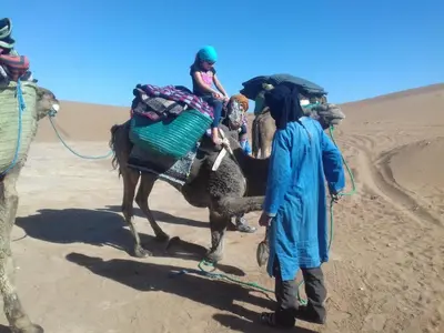 two people riding on a camel in the desert at Chegaga Berber Camps in Mhamid