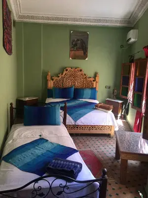 a bedroom with two beds with blue and white sheets at Riad Selma in Meknès