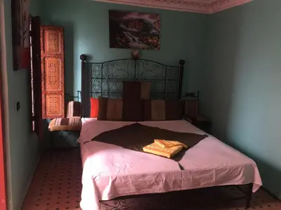 a bedroom with a large bed with pink sheets at Riad Selma in Meknès
