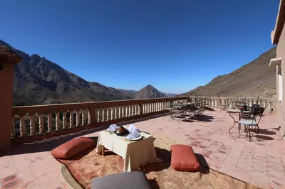 a patio with tables and chairs and mountains in the background at Gite Ogog Tacheddirt in Tacheddirt