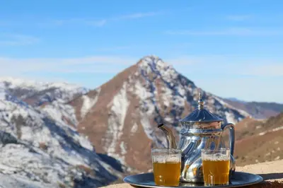 a tea pot and two glasses of beer on a plate with mountains at Gite Ogog Tacheddirt in Tacheddirt