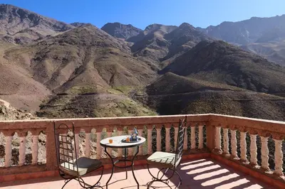 a table and chairs on a balcony with a view of mountains at Gite Ogog Tacheddirt in Tacheddirt